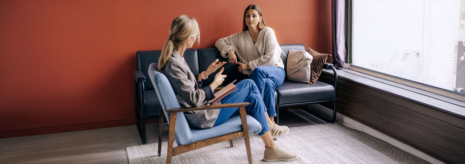 Two people sitting opposite each other on armchairs, one speaking and one listening