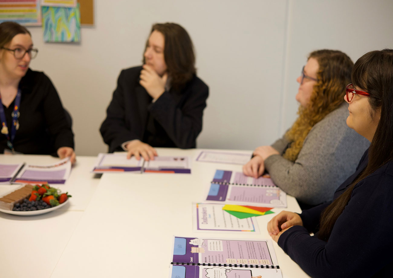 Four EmpowerED team members working at a table and looking at documents together